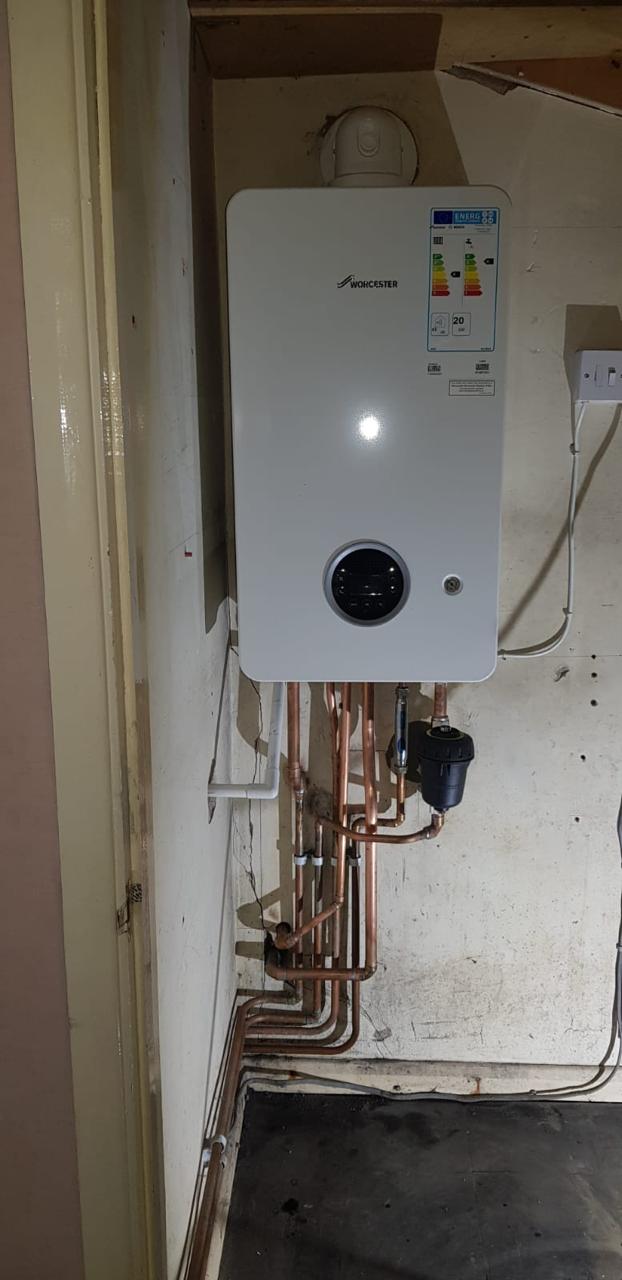 Worcester combi boiler in a hallway cupboard with a horizontal flue and system filter