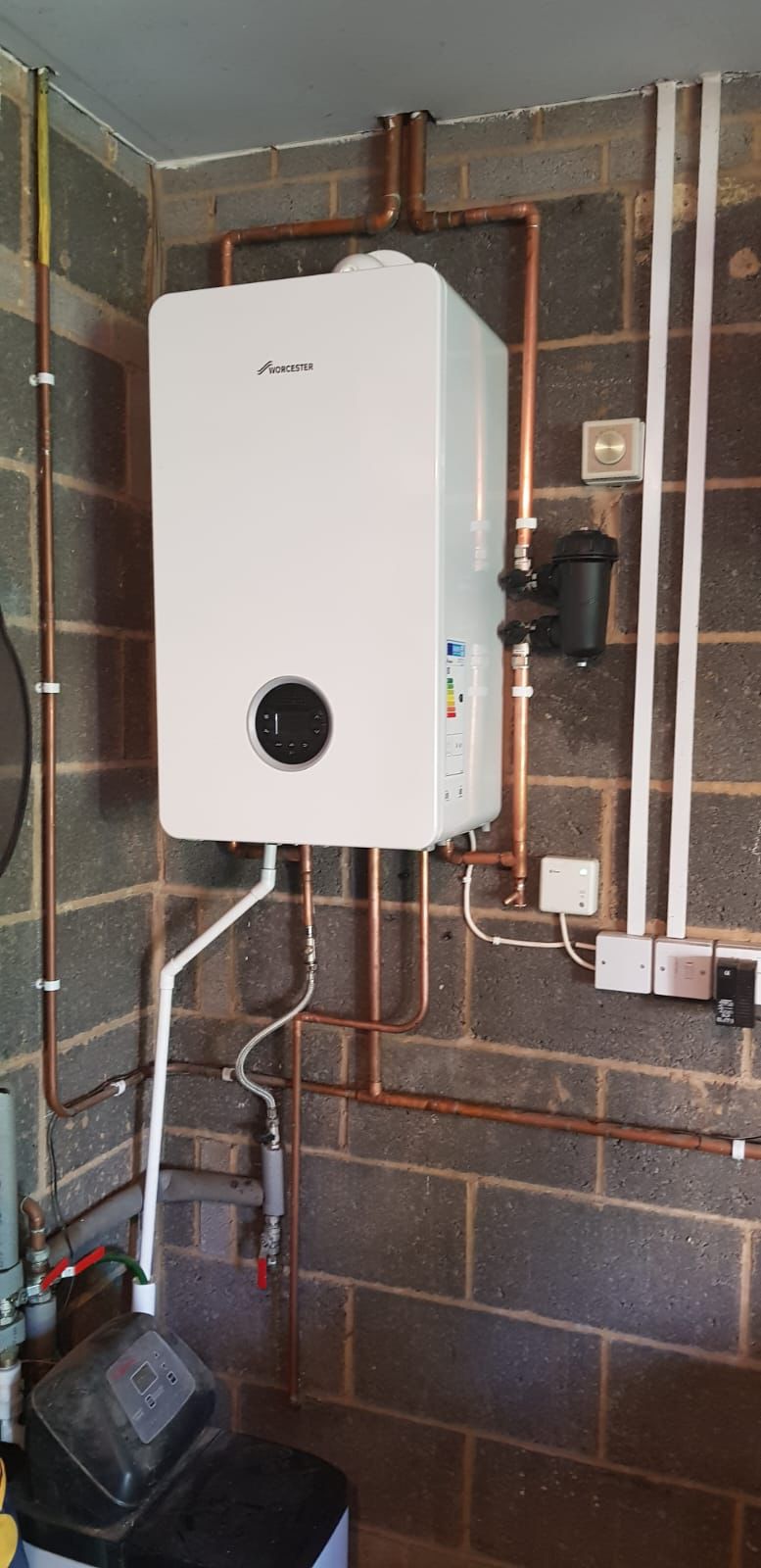 High efficiency Worcester Bosch boiler replacing an old unit on a garage brick wall