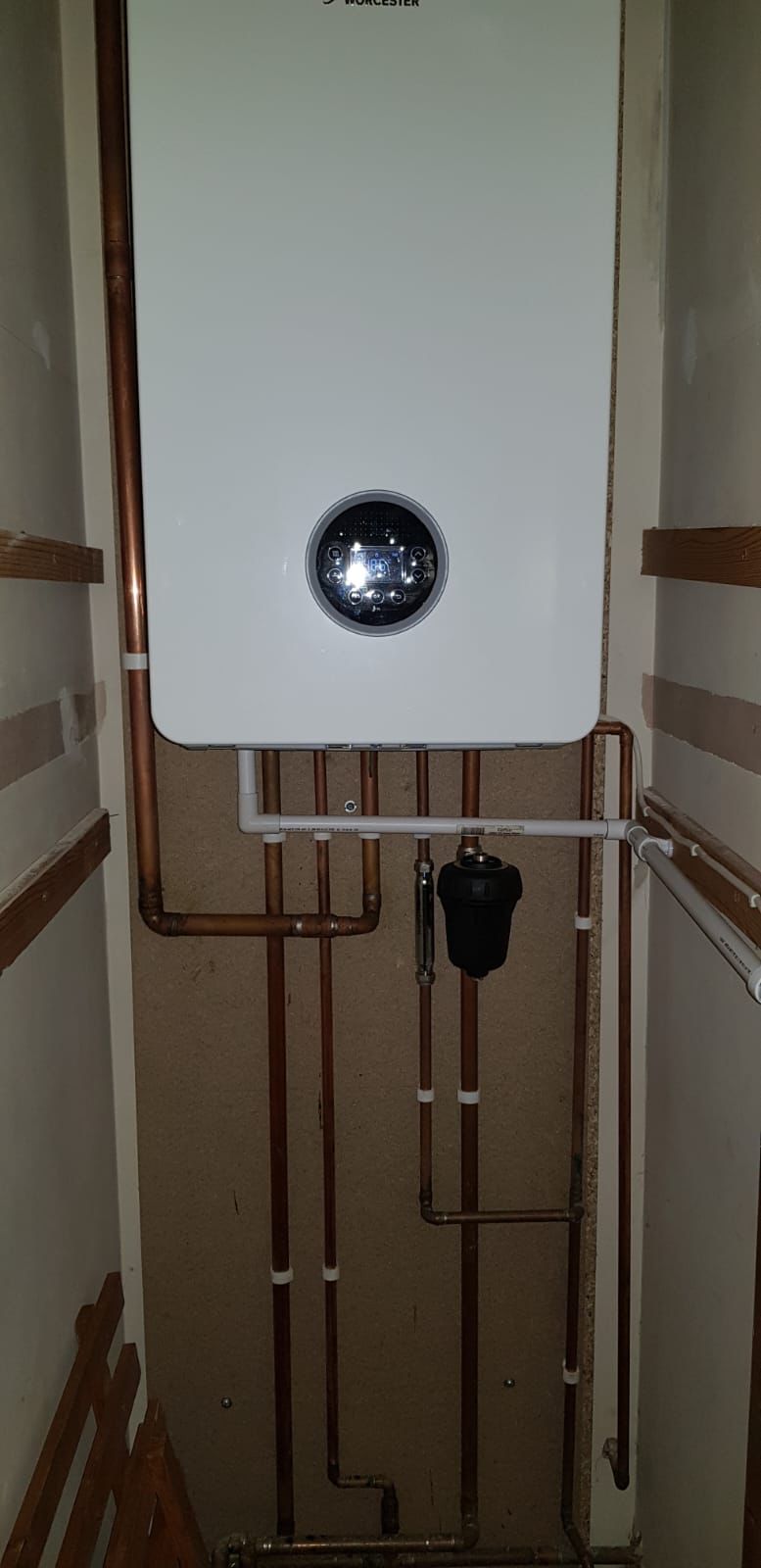 Relocated boiler in an understairs cupboard with tidy vertical copper pipework